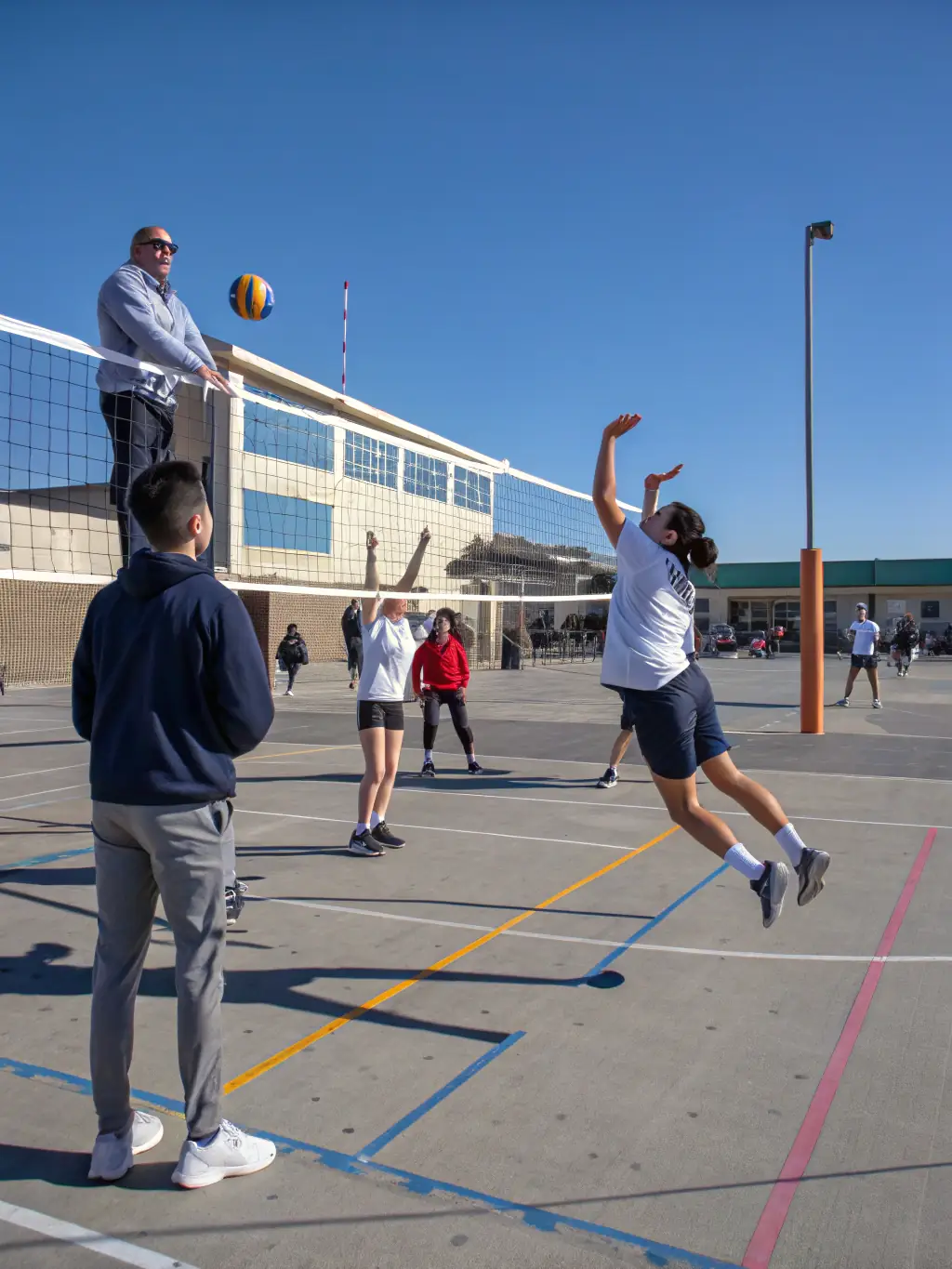 A volleyball team practicing their serves and spikes in the school's volleyball court, emphasizing coordination and strategy.